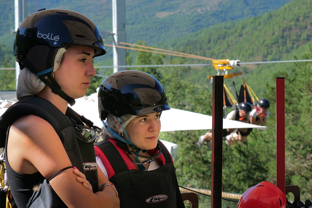 Pareja preparada con arneses y cascos en la plataforma de salida de la tirolina.